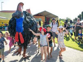 Children play with a larger than life costumed cassowary