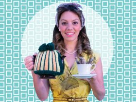 A young woman in yellow 1950s dress and pearls holding a teacup and teapot with striped tea cosy